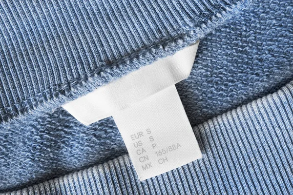 青い繊維背景クローズ アップの小型服のラベル — ストック写真