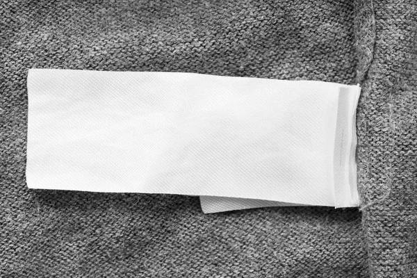 灰色针织背景特写空白白色纺织服装标签 — 图库照片