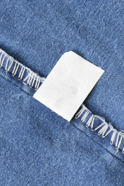 Etykieta Puste Białe Ubrania Niebieski Denim Tło Zbliżenie — Zdjęcie stockowe
