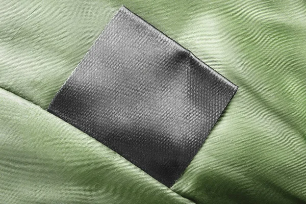 黑色空白衣服标签绿色缎背景特写 — 图库照片