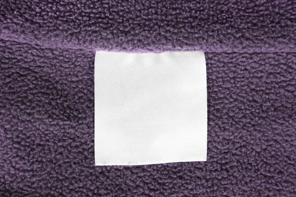 Etiqueta Blanca Ropa Textil Blanco Sobre Fondo Textil Púrpura —  Fotos de Stock
