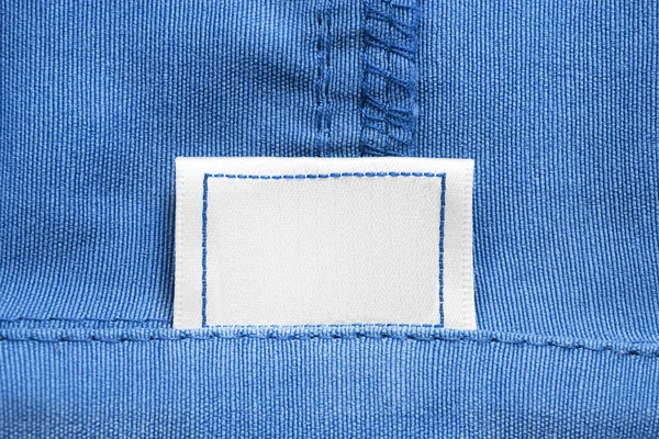 Leere Weiße Textilbekleidung Etikett Auf Blauem Baumwollhintergrund Nahaufnahme — Stockfoto