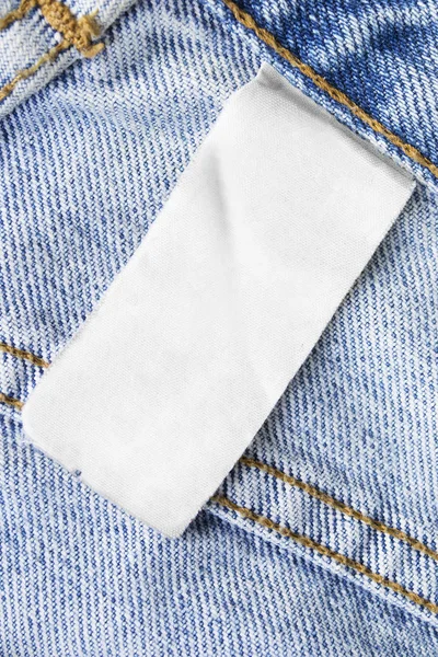 Etiqueta Ropa Blanca Blanco Sobre Fondo Azul Denim Primer Plano — Foto de Stock