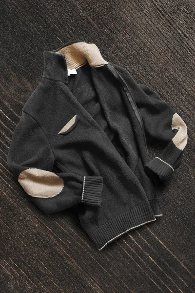 深棕色木制背景上的皱巴巴的针织黑色夹克 — 图库照片