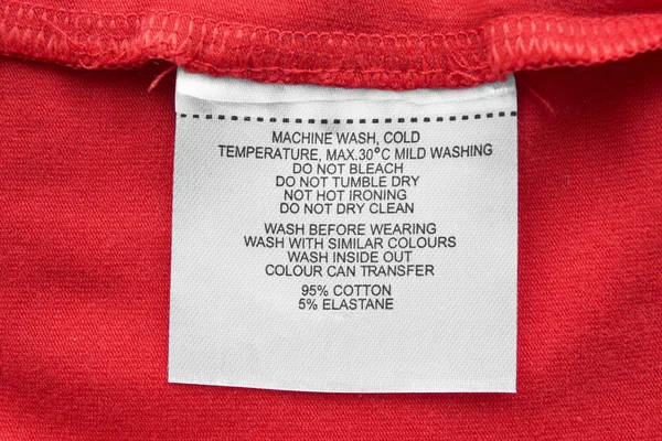 Φροντίδα Και Σύνθεση Ετικέτα Ρούχα Στο Κόκκινο Κλωστοϋφαντουργίας Φόντο Closeup — Φωτογραφία Αρχείου