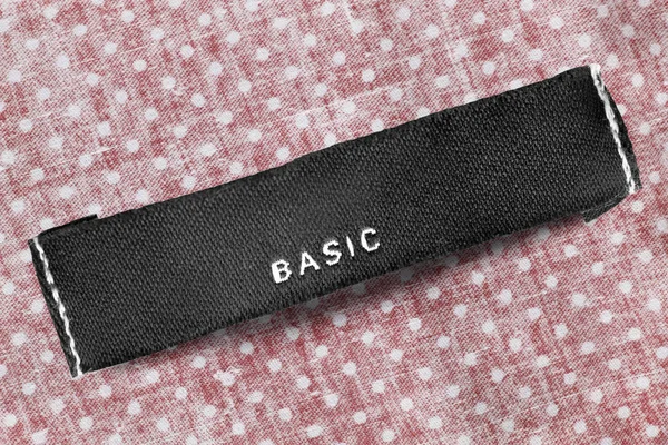 Textile clothes label says basic on cotton polka dots background