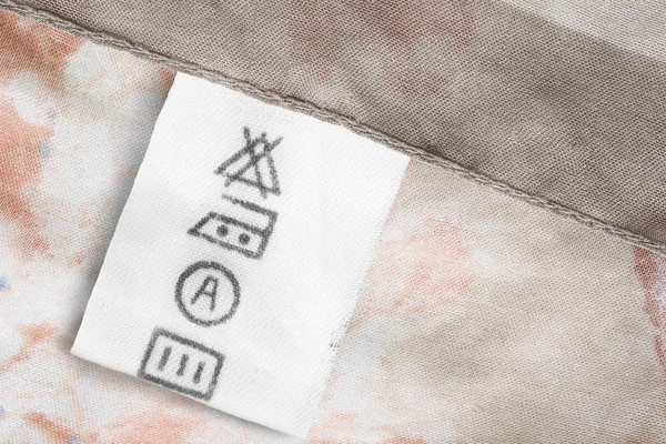 Care clothes label on beige textile background closeup
