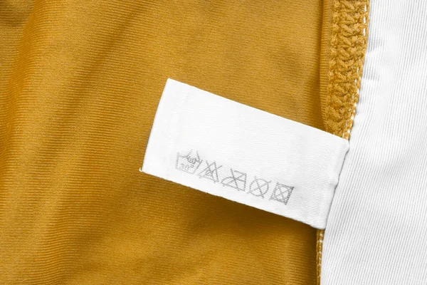 Etiqueta Ropa Cuidado Sobre Fondo Textil Amarillo Blanco — Foto de Stock