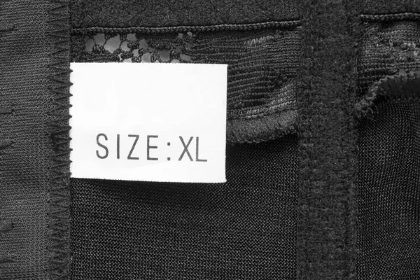 Size XL clothing label on black textile background