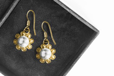 Siyah mücevher kutusunda beyaz inciler olan klasik altın rengi küpeler.