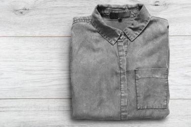 Beyaz ahşap arka planda katlanmış gri kot gömlek