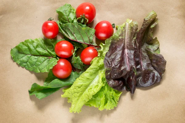 Group of cherry tomatoes and leaf lettuce on craft paper background