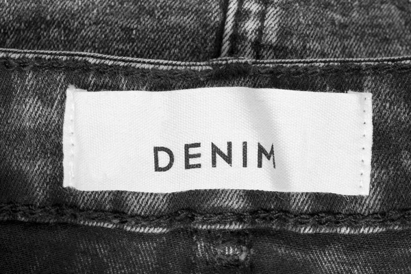 Clothing label says denim on black denim background