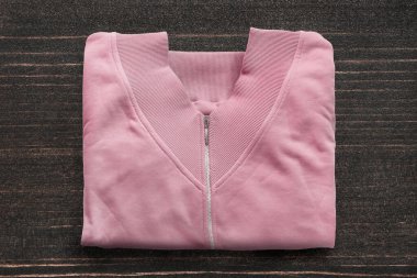 Koyu ahşap arka planda katlanmış pembe kazak.