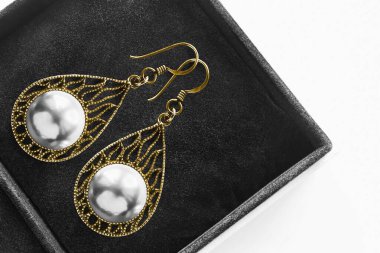 Siyah mücevher kutusuna oyulmuş beyaz inci küpeler.