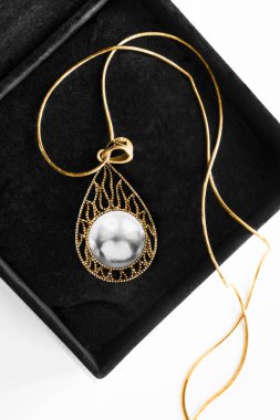 Zarif oyulmuş altın kolye Siyah mücevher kutusunda büyük beyaz inci