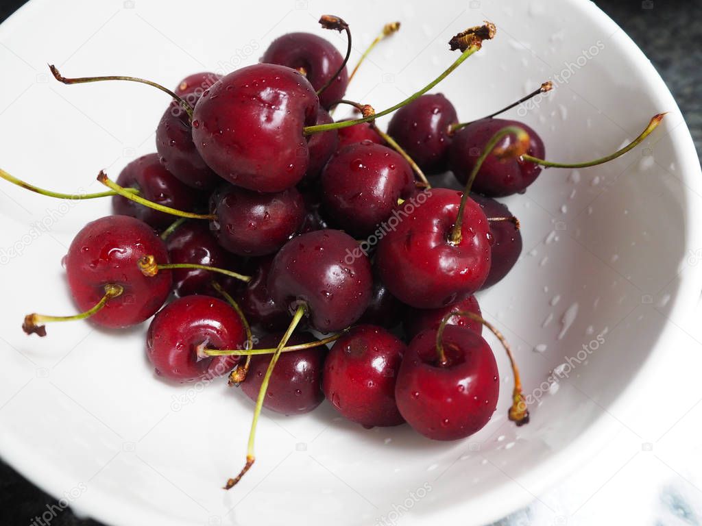 Delicious red cherries in a white cup.