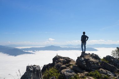 cliff üzerinde duran ve Vadisi ve gündüz dağlarda bakarak adam