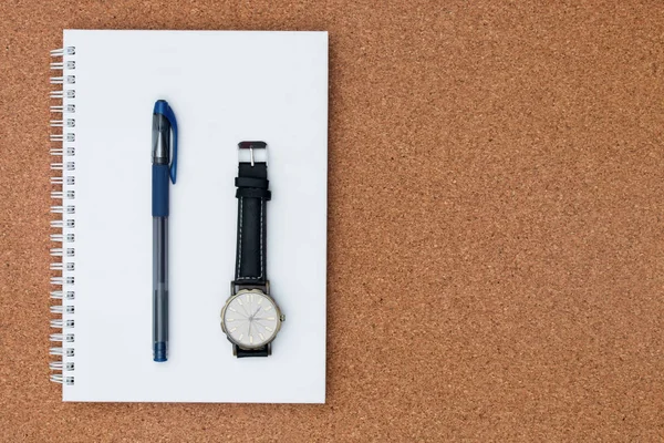 Ручка и часы место на записной книжке на деревянном фоне — стоковое фото