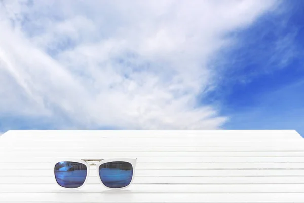 Posto occhiali da sole su legno con nuvole vista cielo . — Foto Stock