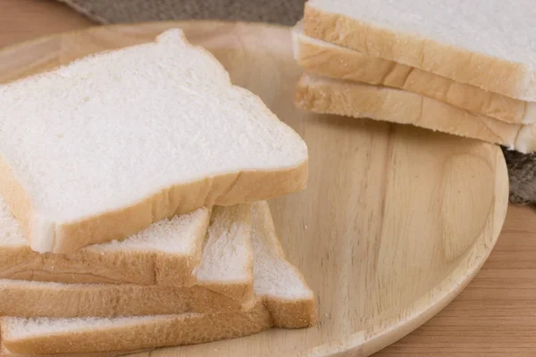 Цілий пшеничний хліб на дерев'яній тарілці, розміщеній на дерев'яному фоні . — стокове фото