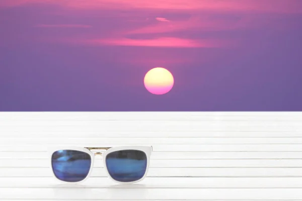 Güneş gözlüğü yer üstünde gündoğumu scape arka plan ile ahşap. — Stok fotoğraf