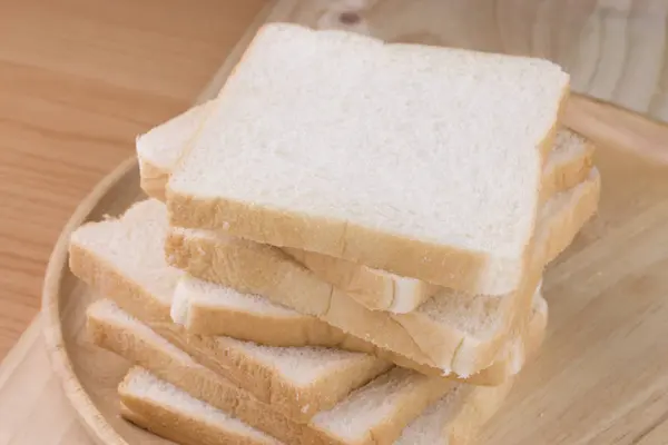 Pan de trigo entero en plato de madera colocado de fondo de madera . — Foto de Stock