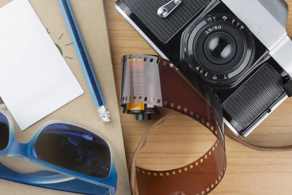 Notebook, potlood, zonnebril en camera op houten vloer. — Stockfoto