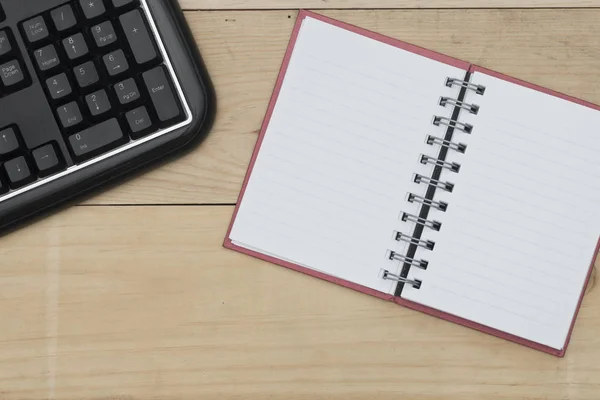 Local de trabalho com teclado e notebook sobre mesa de madeira. — Fotografia de Stock