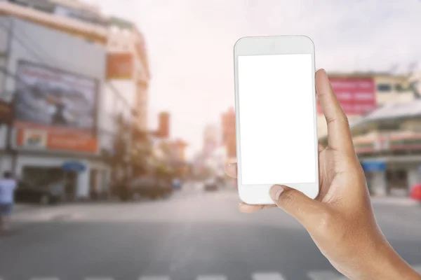 Mano celebración de teléfono inteligente en la carretera de tráfico y la escena urbana . —  Fotos de Stock