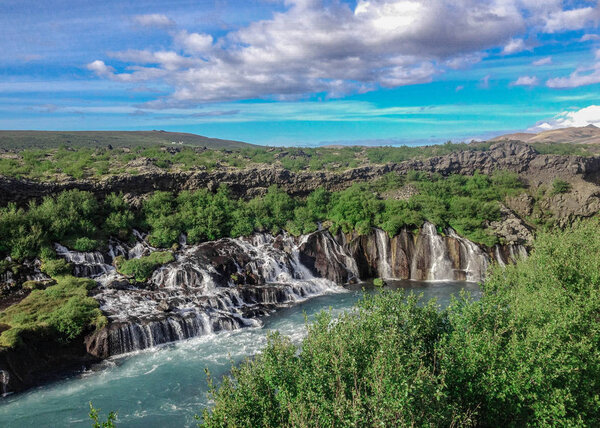 Beautiful and unusual natural phenomena Lava falls Hraunfossar: azur water seep through the lava and run as tiny waterfalls and rapids into Hvita River, Borgarfjordur region, West Iceland, Europe