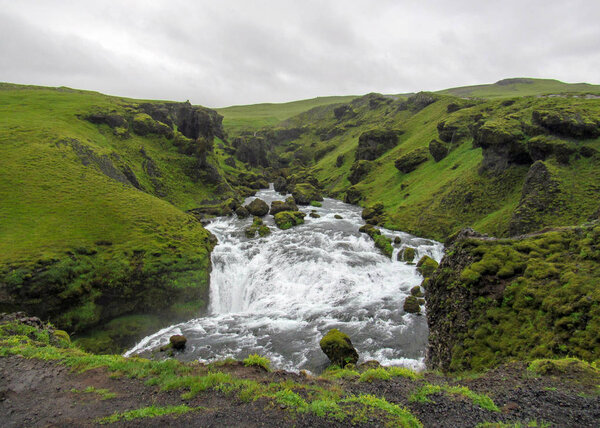 Beautiful mossy landscape along the Skoga river canyon with waterfall in rainy summer day on the Fimmvorduhals Trek from Skogar to Thorsmork, Highlands of Iceland