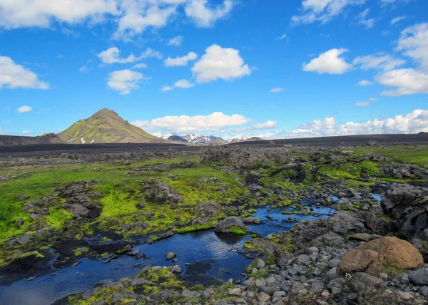 Breathtaking view on tiny river with bright green mossy banks flows from Myrdalsjokull through volcanic barren landscape, hiking on the Laugavegur Trail between Emstrur-Botnar and Alftavatn, Iceland