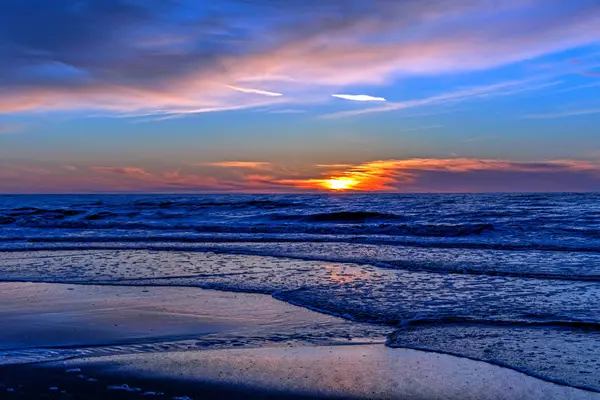 Homok strand végtelen horizonton, és habos hullámok alatt ragyogó naplementés sárga színek és felhők felett a tenger — Stock Fotó