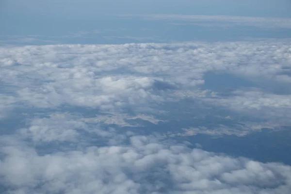 Luftaufnahme aus dem Flugzeugfenster mit blauem Himmel und weißen Wolken — Stockfoto