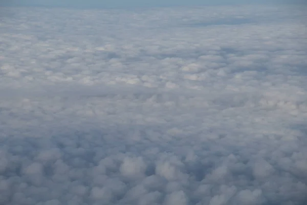 Luftaufnahme aus dem Flugzeugfenster mit blauem Himmel und weißen Wolken — Stockfoto