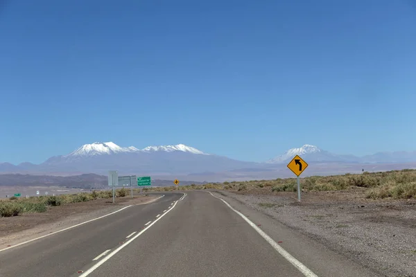 Rota vire com sinal de estrada amarelo no deserto do Atacama, Chile — Fotografia de Stock