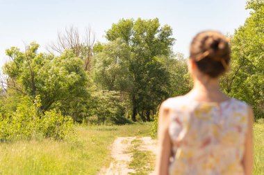 Kiev, Ukrayna, ülkede yol yakın ayakta bir chignon bir kadınla mesafe ağaçlarda gözlemler. Kadın silüeti yak²n odaklı bir arka plan olduğunu.