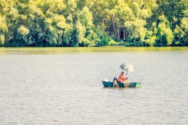Kiev, Ukrayna - 25 Ağustos 2015 - bir adam, bir balıkçı, Kiev Dnieper Nehri üzerinde bir gemide. O kendini Balık tutma sırasında sıcak yaz güneşten korumak için bir şemsiye kullanır