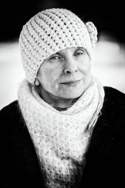 戴着一顶羊毛帽子和围巾 搭配雪背景的高级成人女子冬季肖像 — 图库照片