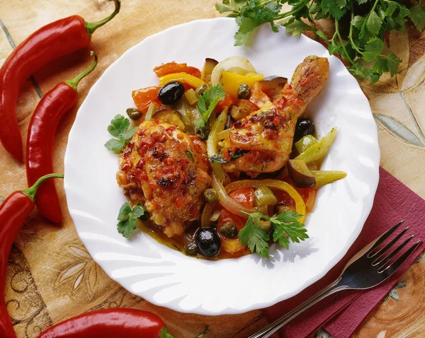 野菜と鶏肉の煮込み タマネギ コショウ オリーブ セロリ エンドウ豆 テーブルで提供していますが 白いプレートに赤唐辛子 ストック画像