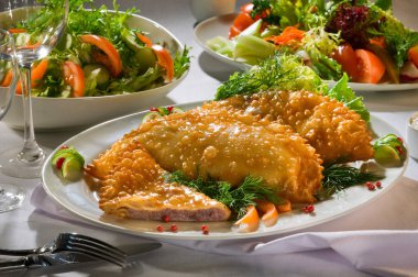 Chebureks, pasties sığır çatal bıçak takımı ile beyaz tabakta, plakaları hizmet bir masada beyaz masa örtüsü üzerinde sebze salatası ile