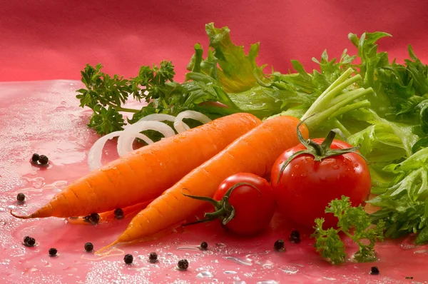 野菜なニンジン オニオン リング エンドウ豆 パセリ 赤の背景にレタスとトマト — ストック写真