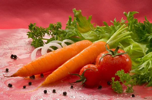 野菜なニンジン オニオン リング エンドウ豆 パセリ 赤の背景にレタスとトマト — ストック写真