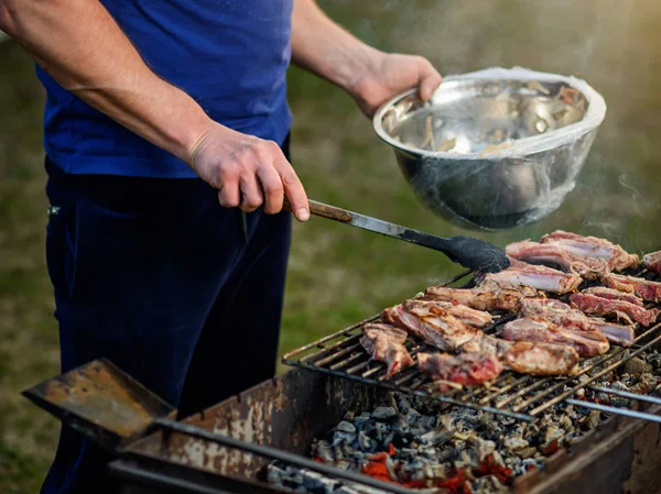    Metal maşa ile adam eli ızgara kuzu parçaları döner