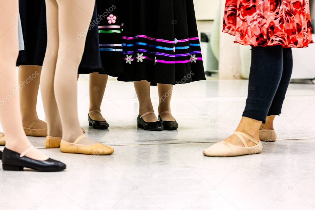 Group of young girl ballet students with teacher during practice for character study class. Ballet slippers, character shoes, stockings and character skirt. Landscape format with copy space worms view. Inspiration for poster or meme for ballet school
