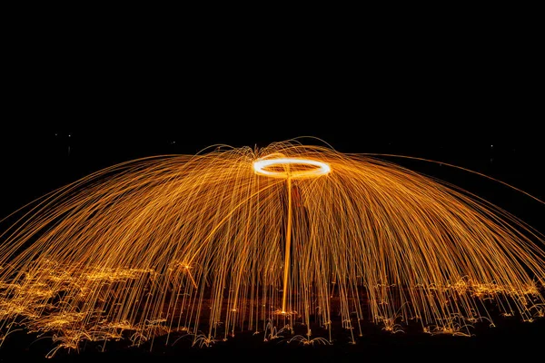 Steel wool burning overhead, spinning steel wool against night sky making fiery waterfall patterns in the dark. Inspiration for meme, blog or poster for creative concepts with unusual objects. Landscape format
