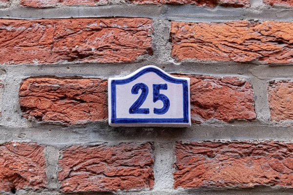 House number twenty-five 25 painted on white ceramic tile in blue from France