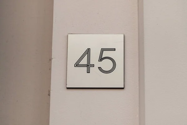 House number forty-five 45 etched into layered plastic with a three D 3D effect attached to a white door frame in Sweden