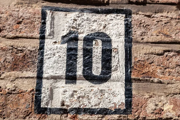 House number ten 10 painted black on white rectangle on brickface in stylised font from France